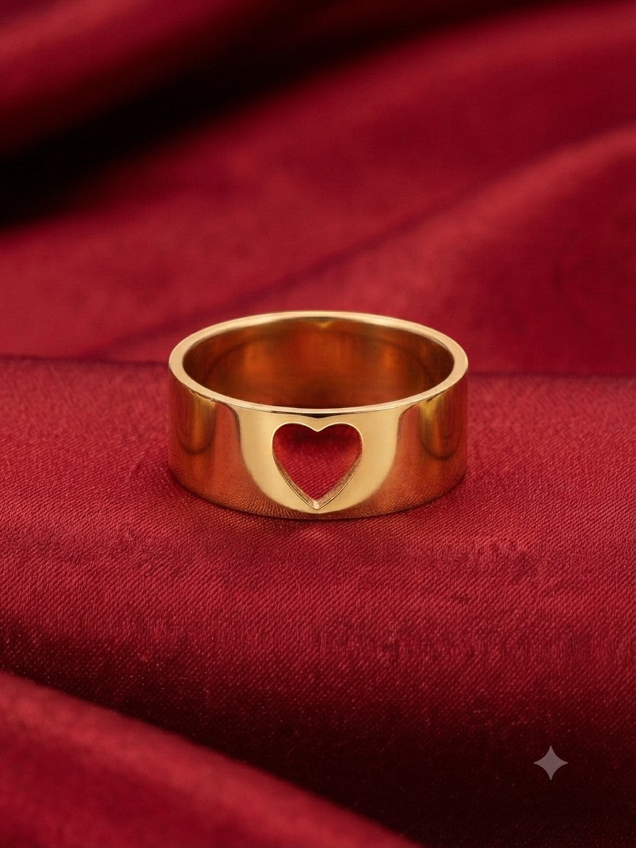 JOYAS gold band ring featuring a delicate heart-shaped cutout on a luxurious red satin background